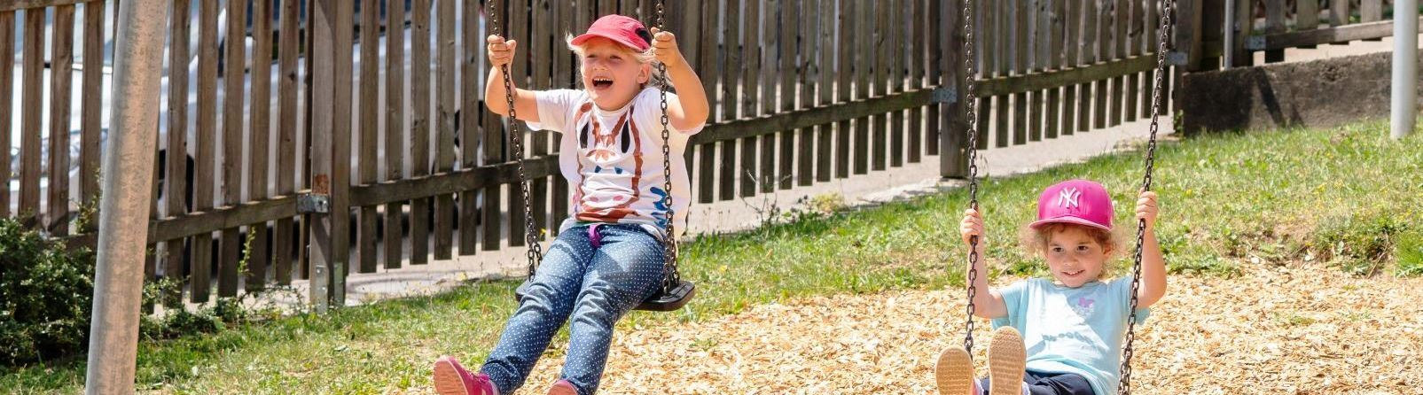 Zwei Kinder schaukeln.