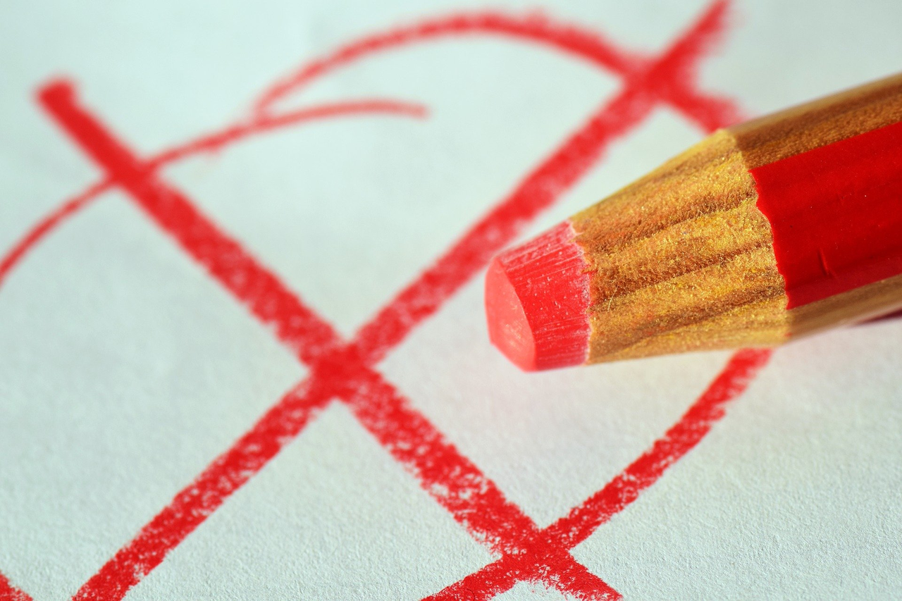 Roter Holzstift vor rotem Kreis mit Kreuz